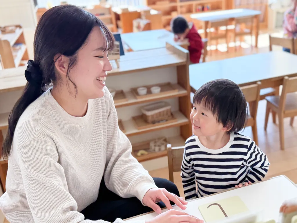 保育士と園児が笑顔で見つめ合いながら活動している様子