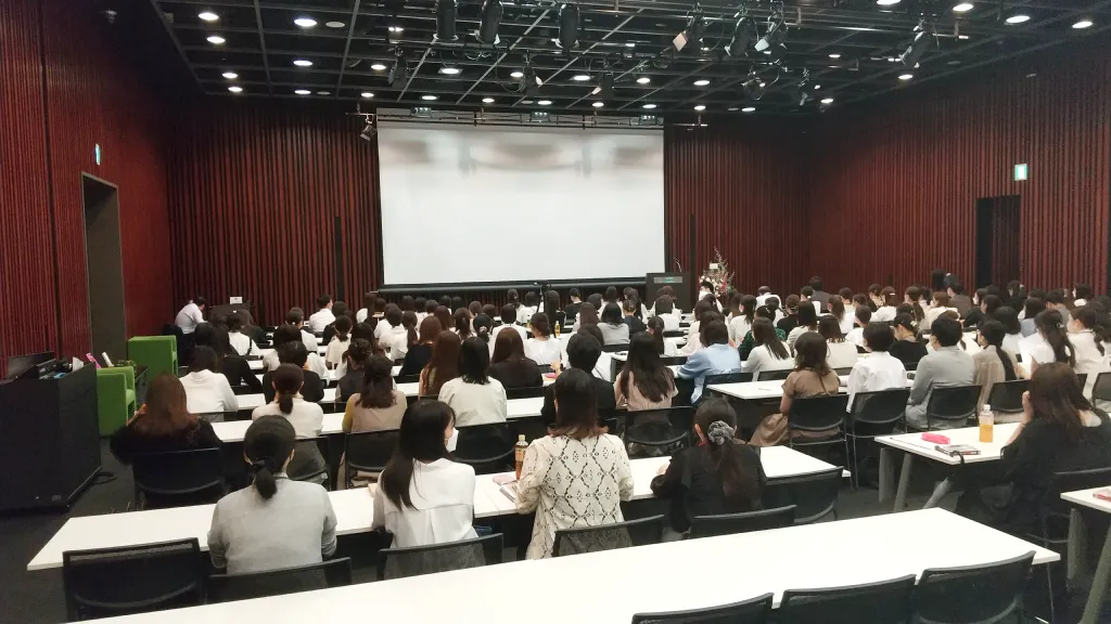 広い会場で大勢の職員が研修を受けている様子